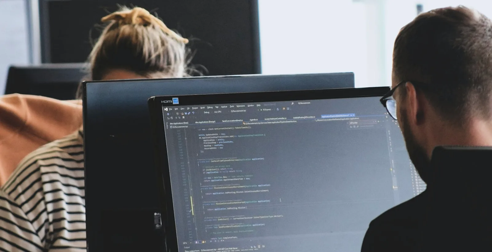Two developers at monitors with code on screen